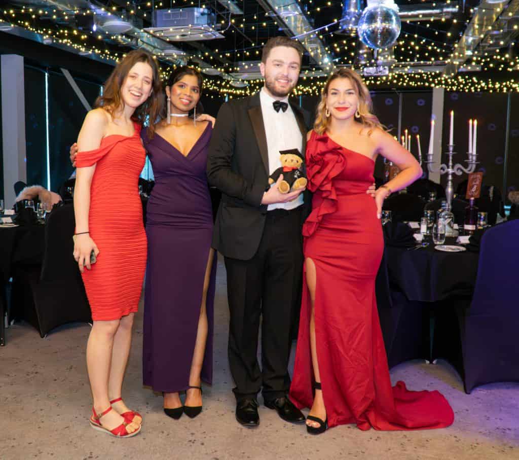 Elegant group of young adults celebrating at a formal event with stylish attire and festive decor.